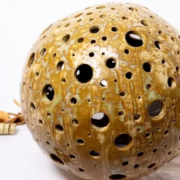 Esfera decorativa de ceràmica amb perforacions manuals i esmalt brillant color ocre d'Art Ceràmic.